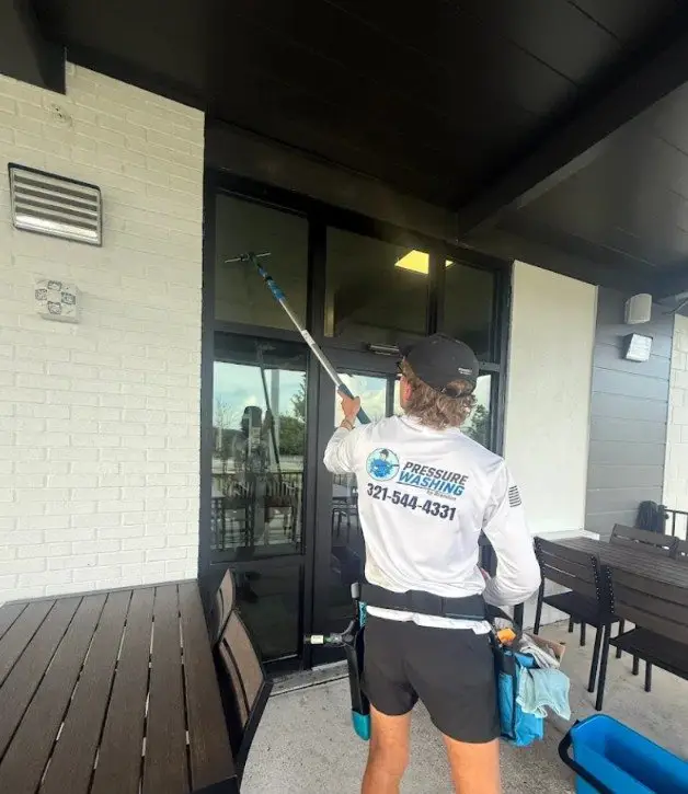 Technician cleaning restaurant windows with a water-fed pole in Melbourne, FL