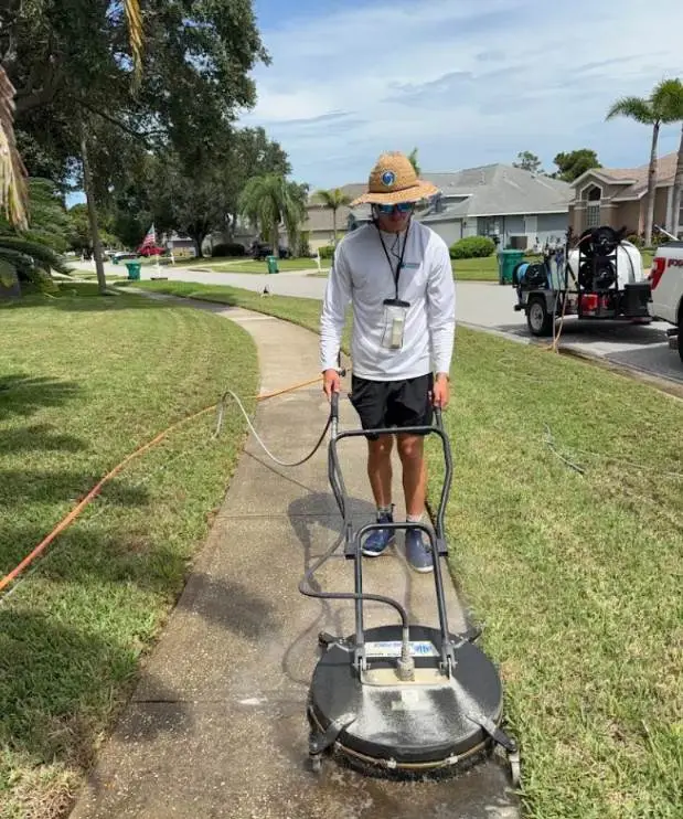 Technician surface cleaning a concrete driveway walkway in Viera, FL