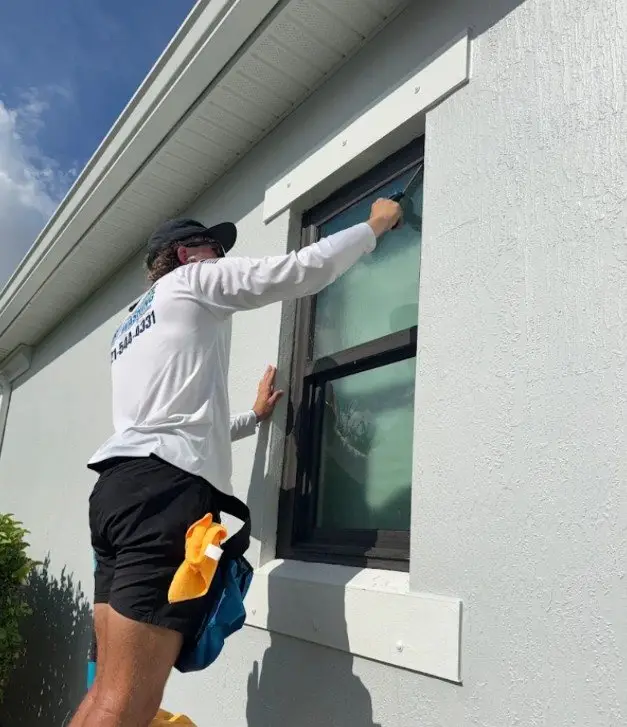 Technician hand cleaning a residential window in Melbourne, FL