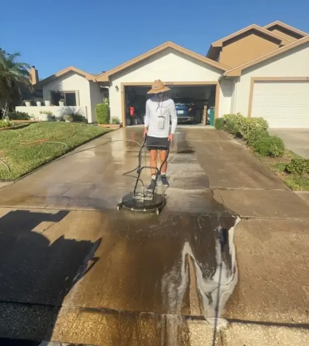 Technician pressure washing a concrete driveway at a Melbourne, FL home