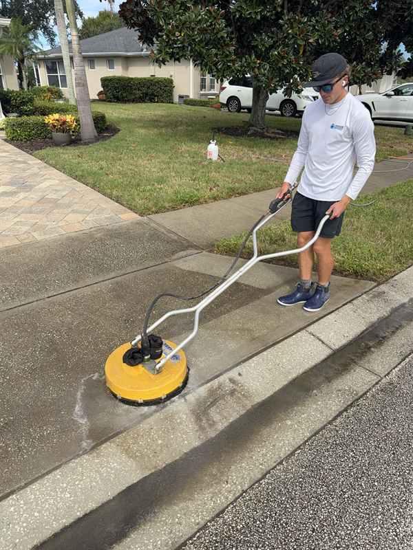 Technician cleaning a sidewalk with a rotary surface cleaner in Rockledge, FL