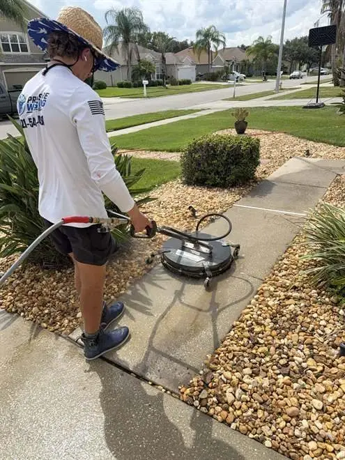 Technician surface cleaning a front walkway beside rock landscaping in Rockledge, FL