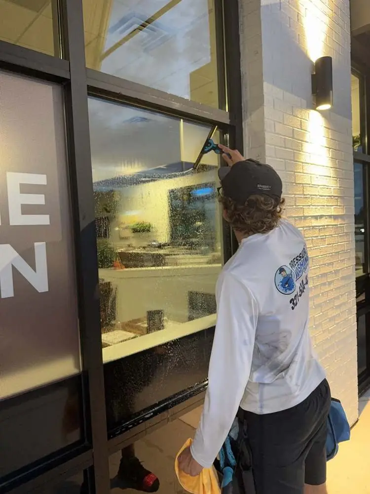 Technician cleaning a storefront window frame in Rockledge, FL